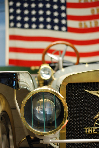 An American flag hangs behind a car.