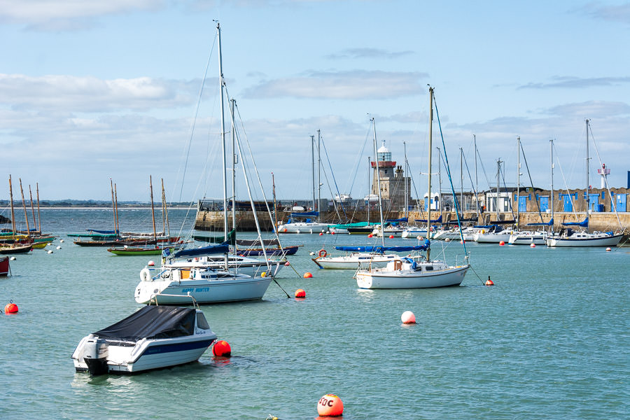 Docked boats dot the Howth Harbour in front of the Howth Lighthouse.