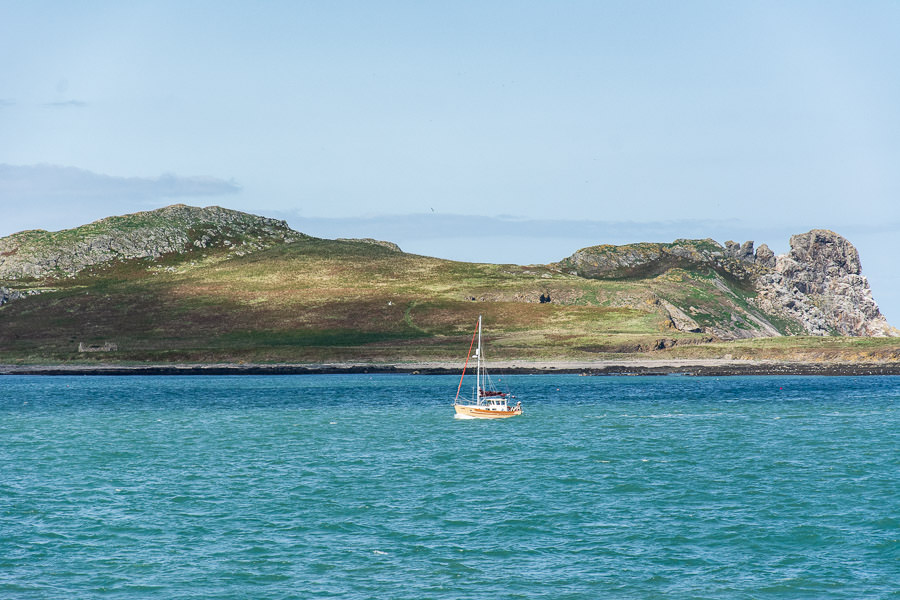 A sailboat enjoys calm waters in front of Ireland's Eye.