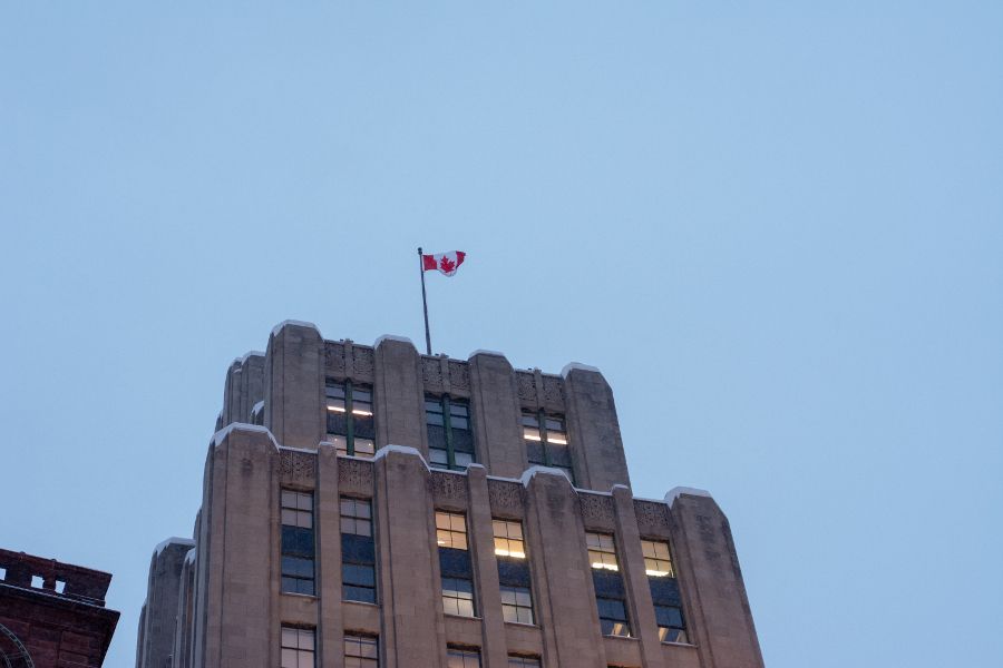 The Canadian flag sits atop an Art Deco building at Place D'Armes in Montreal.