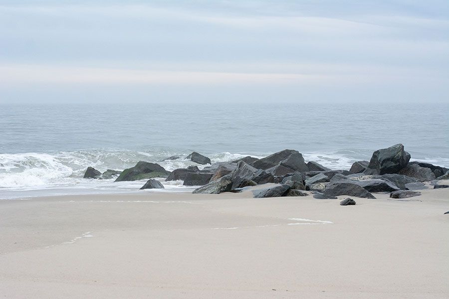 Waves lapping at the stone jetty on the beach.