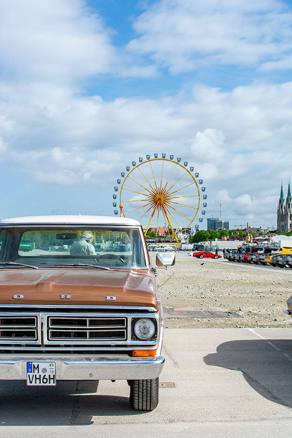 A Ford pick up truck on show at the ACM Oldtimer-Treffen with the Munich Frühlingsfest Ferris wheel in the background.