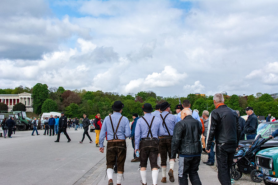 A group of men in bowler hats and Lederhosen stroll across the Wiesn.