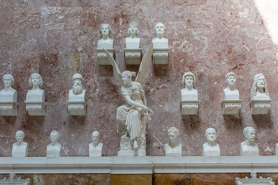 A wall of busts honoring famous Germans and an angel sit along a wall inside of Walhalla.