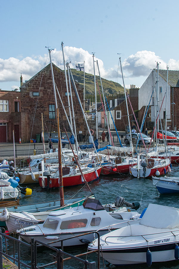 Sailboats float in the harbor at the North Berwick Yacht Club with North Berwick Law in the background.