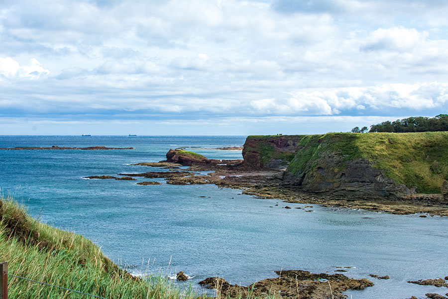 The green cliffs jut into Oxroad Bay in North Berwick, East Lothian, Scotland.