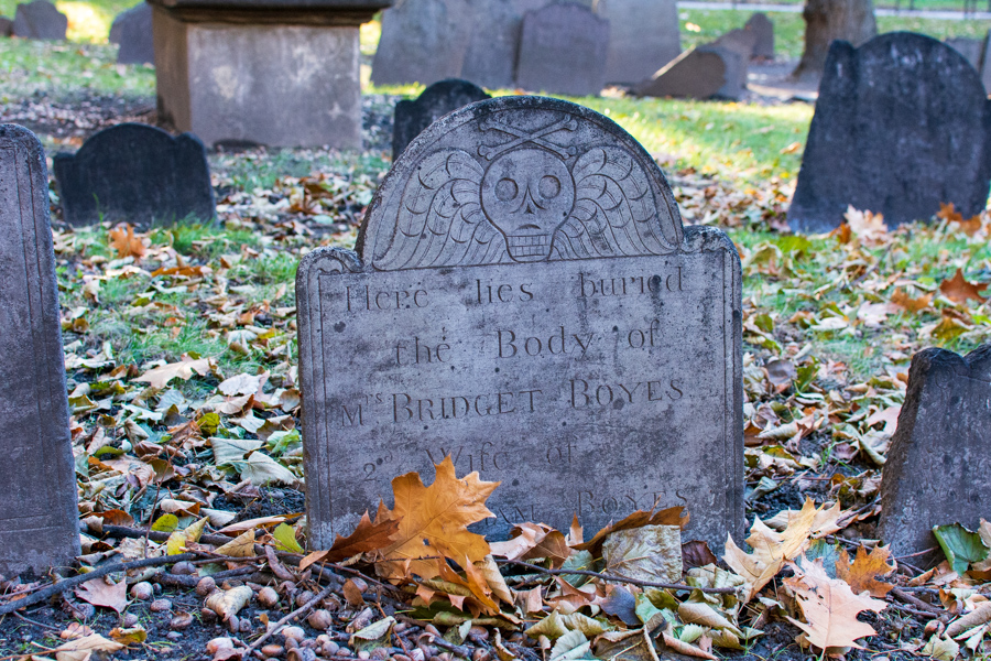 A stone headstone among the leaves at Granary Burying Ground in Boston.