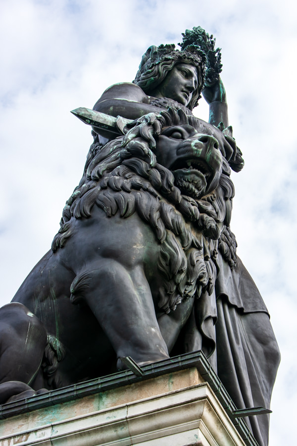 A lion sits proudly at the feet of the Bavaria statue.