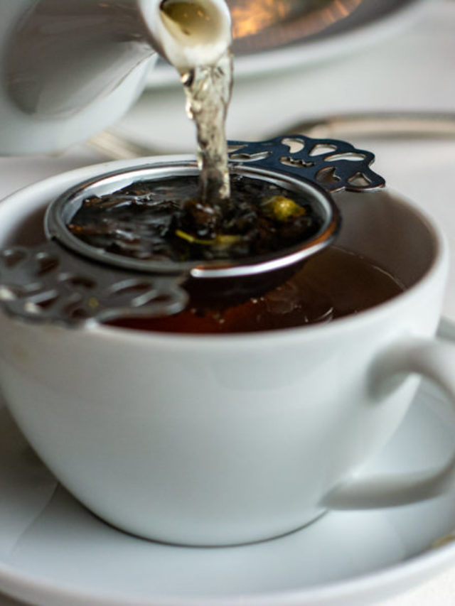 Pouring loose leaf tea into a strainer and cup.