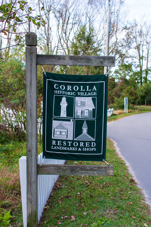 A green banner marks Historic Corolla Village, restored landmarks and shops.