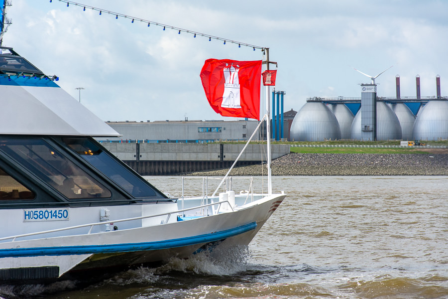 A ship flying a Hamburg flag cruises up the river.