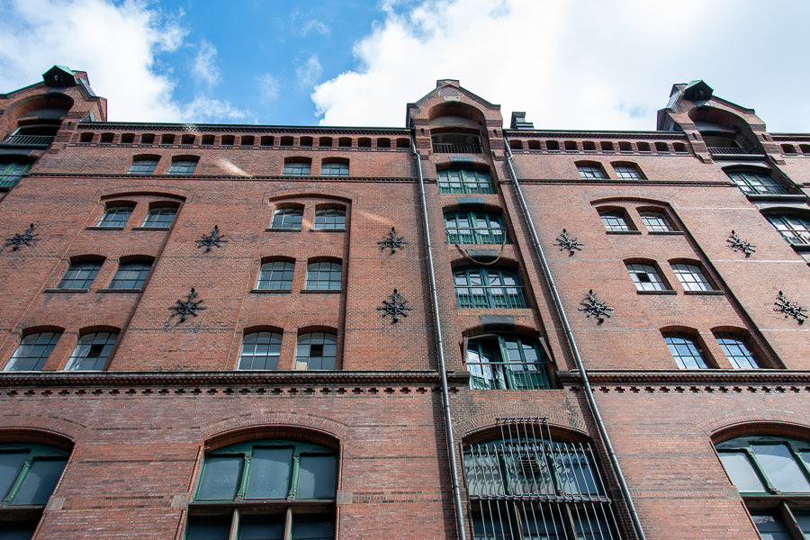 The brick walls of the warehouses of the Speicherstadt rise over the canals of Hamburg.