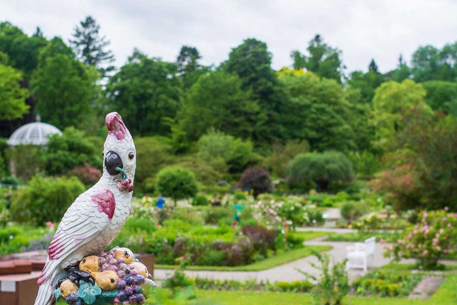 A parrot figurine by Nymphenburg Porcelain sits overlooking a garden.