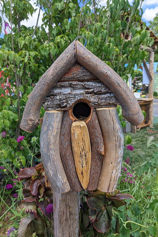 A bee rests inside a bird house.