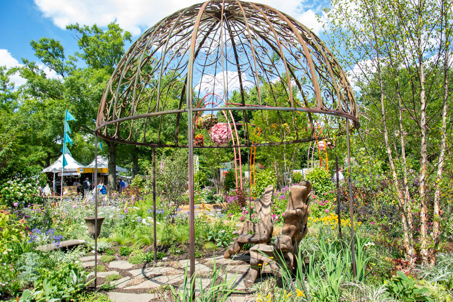 A metal gazebo sits amongst a garden at the Philadelphia Flower Show.