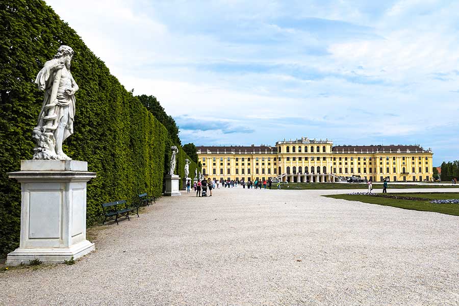 Behind Schönbrunn Palace statues line garden hedges.