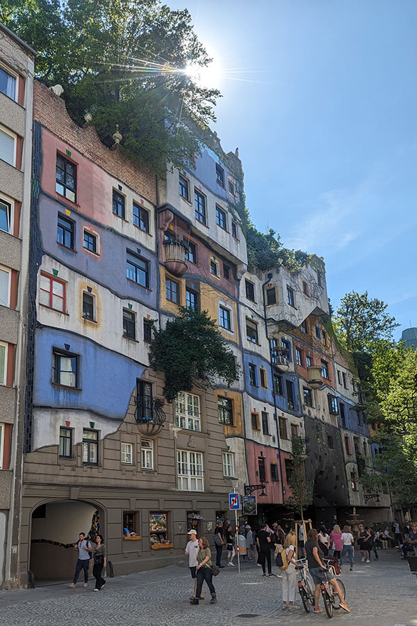 Street view of Hundertwasserhaus in Vienna, Austria, with its colorful facade and unique design attracting visitors.