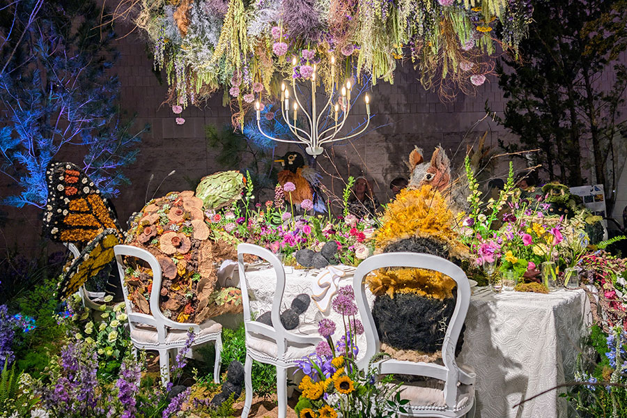 Friendly backyard insects and critters dine at a table in the Jennifer Designs exhibit at the Flower Show 2025.